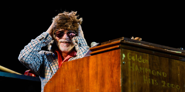 Helge Schneider sitzt mit Sonnenbrille an einer Hammond-Orgel und hält seinen Kopf