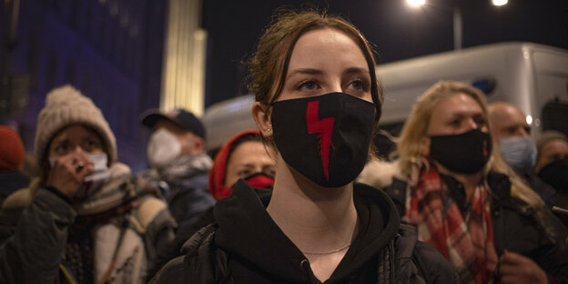 Demonstrierende mit Mundnasenschutz, auf dem das rote Blitzsymbol der Pro-Choice-Bewegung abgebildet ist