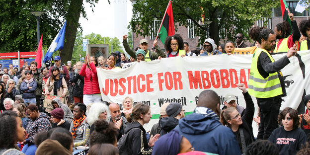 Menschenansammlung mit einem Banner mit der Aufschrift "Justice For Mbobda".