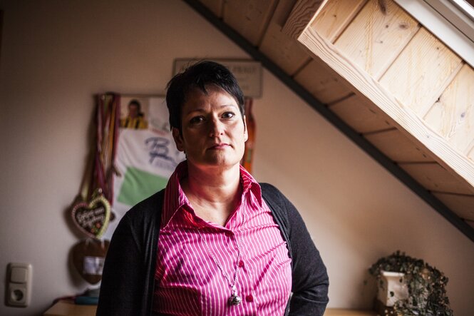 Birgit Birner, pinke Bluse, Kurzhaarfrisur, steht im Zimmer unter einem Dachfenster.