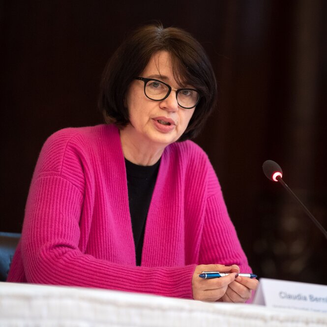 Bremens Gesundheitssenatorin Claudia Bernhard spricht bei einer Pressekonferenz. Sie trägt schwarze kinnlange Haare, eine dunkle Hornbrille und eine pinke Strickjacke