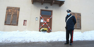 Ein Polizist steht vor einer mit Absperrband verschlossenen Tür