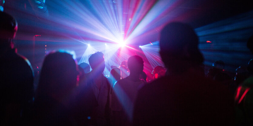 Umrisse von Menschen in einem Club, buntes Licht.