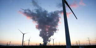 Rauch eines Kohelkraftwerks, drumherum Windräder