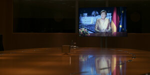 Bildschirm, auf dem Angelas Merkel zu sehen ist, wie sie im Fernsehen ihre Neujahrsansprache hält