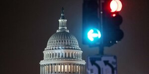 Kuppel des US-Kongresses bei Nacht. Davor eine Ampelanlage mit einem grünen und einem roten Ampellicht