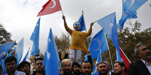 Türkei, Istanbul: Ein Kind aus der muslimischen Volksgruppe der Uiguren trägt bei einem Protest gegen den Umgang mit der Minderheit in China eine türkische Fahne und eine Maske in den Farben der uigurischen Unabhängigkeitsbewegung.