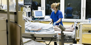 Eine Pflegerin behandelt einen Patienten in einem Klinikbett