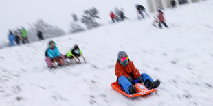 Kinder rodeln mit Schlitten auf dem Wachberg in Leipzig