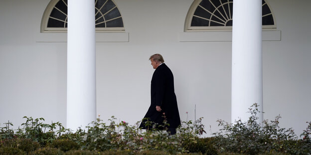 Donald Trump geht an zwei Säulen am Weißen Haus entland