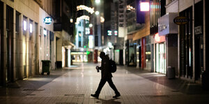 Ein Mann läuft nachts über eine ansonsten verlassene Straße