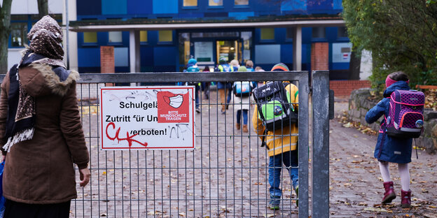Eine geschlossene Schule: an einer Tür hängt ein Schild mit "Bitte Maske tragen"