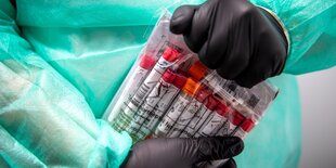 Proben für einen PCR-Test werden von einem Mitarbeiter im Corona-Testzentrum verpackt