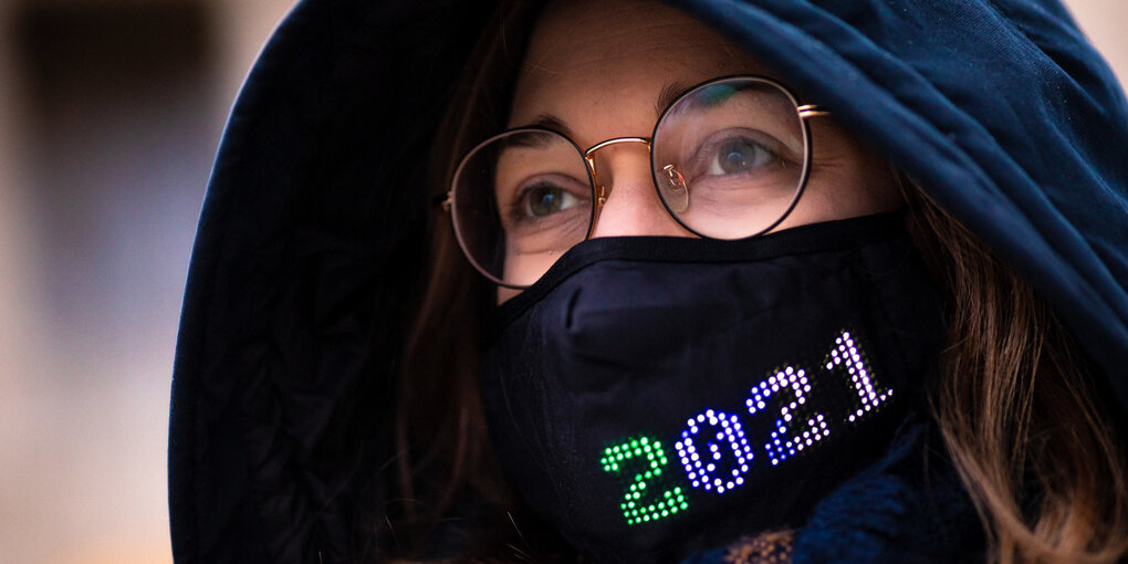 Eine Frau trägt eine Maske mit dem bunten Schriftzug 2021