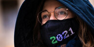 Eine Frau trägt eine Maske mit dem bunten Schriftzug 2021