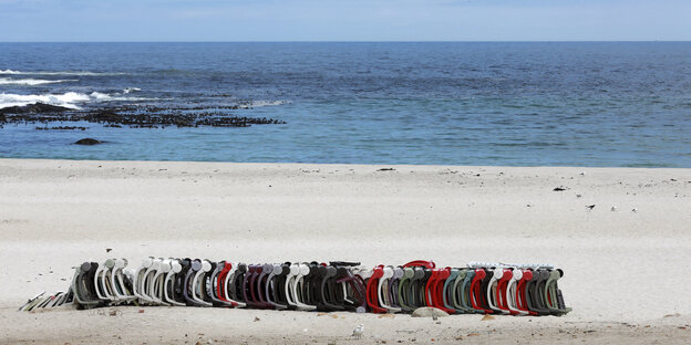 Liegestühle liegen zusammengesteckt am Strand von in Kapstadt