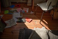 Auf dem Boden eines Kinderzimmers liegen Schulsachen verstreut