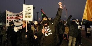 Mehrere Schwarze mit Protestschildern auf einer Straße im Abendlicht