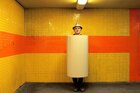 Der Künstler Jim Avignon vor gelben Kacheln in einer großen Papprolle