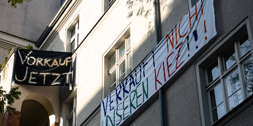 Zwei Plakate hängen von einer Hauswand in neukölln