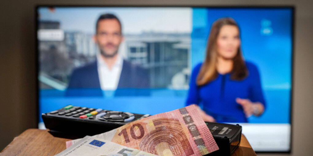 Fernbedienung und Geld vor einem Fernseher