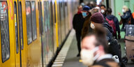 Fahrgäste mit Mund-Nasen-Schutz stehen auf einem U-Bahnhof in Berlin
