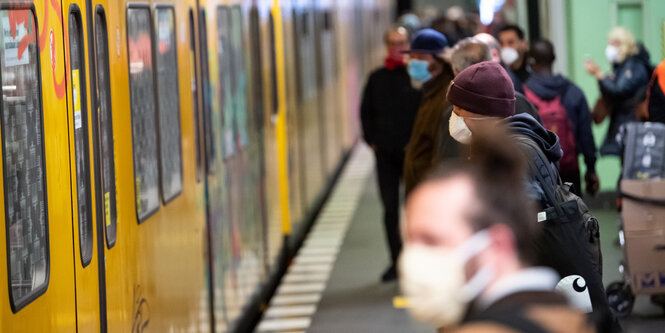 Fahrgäste mit Mund-Nasen-Schutz stehen auf einem U-Bahnhof in Berlin