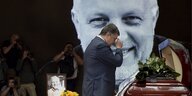 Petro Poroschenko steht an einem Grab im Hintergrund ist das Bild des Verstorbenen groß zu sehen