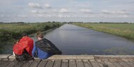 Zwei Menschen mit Cape sitzen auf einer Kanalbrücke