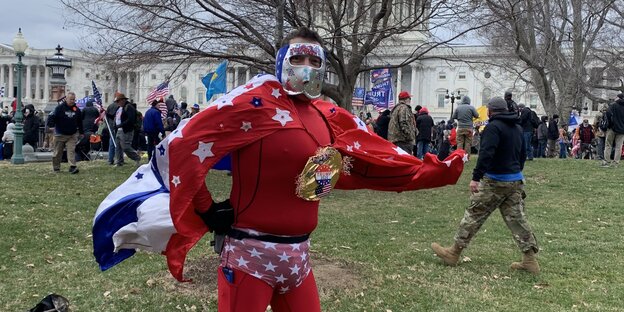 Ein Mann in rotem Cape und silberner Maske posiert vor dem US-Kapitol