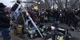 Man schlägt mit Fahnenstange auf TV-Equipment ein