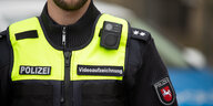 Ein Polizist trägt deutlich sichtbar eine Kamera auf der Schulter