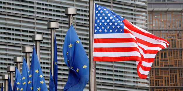 Flagge der Vereinigten Staaten weht im Hintergrund sind Flaggen der Europäischen Union zu sehen
