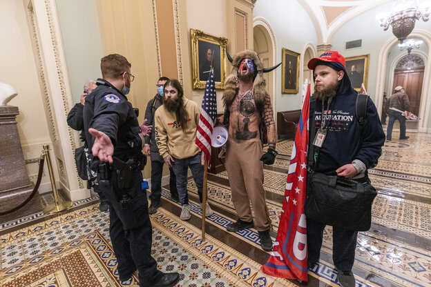 Mit Hörnern und Fell beklediet schreit ein Tätowierter Trumpunterstützer gegen die Polizisten an Mit Hörnern und Fell beklediet schreit ein Tätowierter Trumpunterstützer gegen die Polizisten an