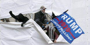 Demonstranten beim Sturm auf das Kapitol auf einem Baugerüst schwenken eine Trump Flagge