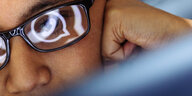 Laptop-Benutzerin blickt auf ein WhatsApp-Symbol, das sich in ihrer Brille spiegelt