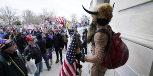 Mann mit aufgesetzen Hörnern und Tatoos und US Flagge vor dem Capitol