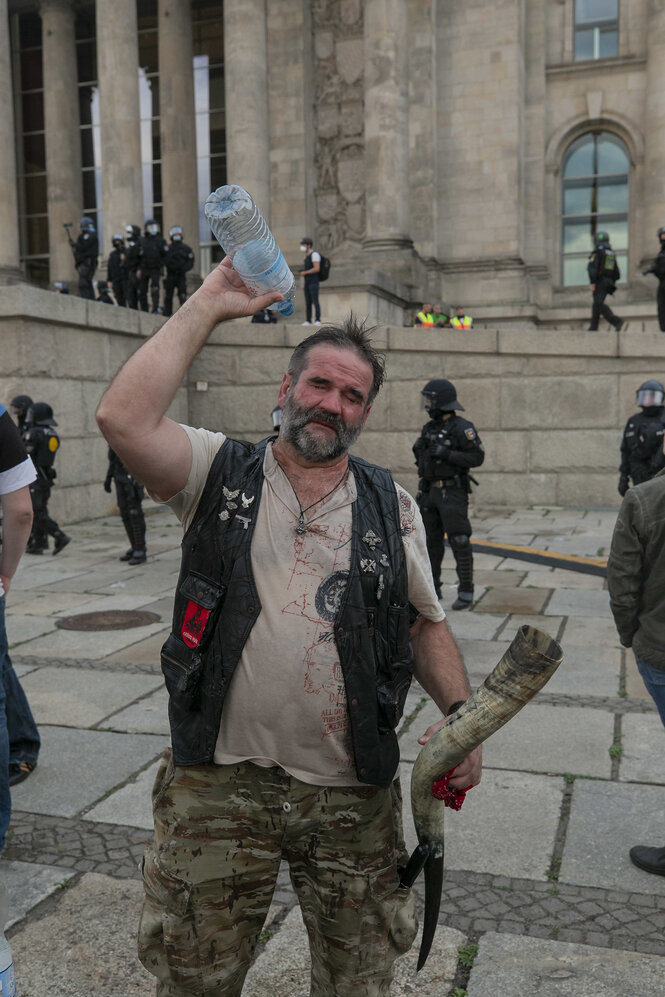 Mann vor dem Reichstag , ein Horn in der Hand, gießt eine Flashce Wasser über sich aus