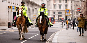 Polizisten auf Pferden reiten in einer fast menschenleeren Straße