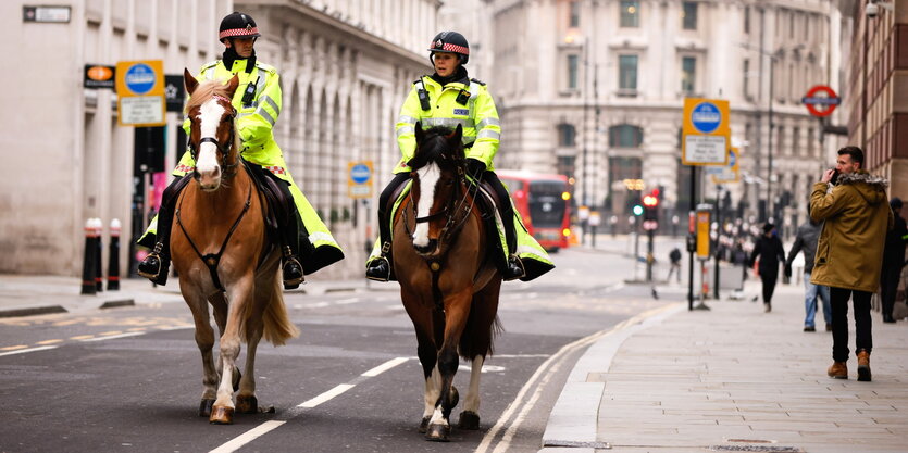 Polizisten auf Pferden reiten in einer fast menschenleeren Straße