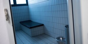 Eine Gewahrsamszelle in Köln; in dem verkachelten Raum gibt es ein einfaches Bett und eine Stahltoilette