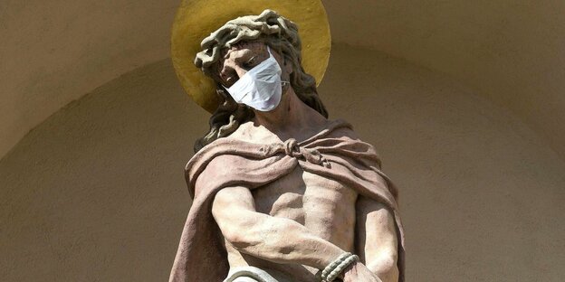 Eine Statue von Jesus, die eine Maske trägt.