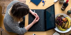Eine Frau sitzt an ihrem aufgeklappten Laptop