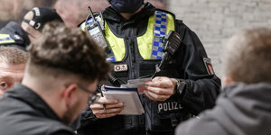 Polizist kontrolliert die Papiere von drei jungen Männern.
