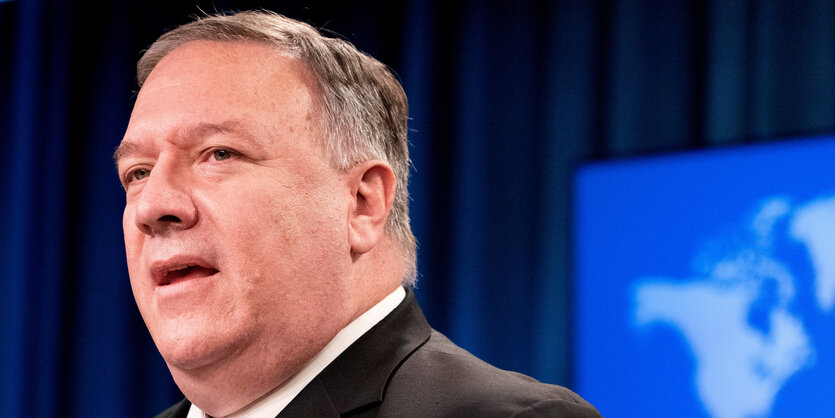 Mike Pompeo steht vor einem Monitor