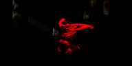 Szene aus Christine Umpfenbach Rechercheprojekt zum Oktoberfestattentat: Eine Person springt in rotes Licht getaucht in die Höher