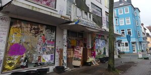 Eine Hausfassade mit Graffiti, Transparenten und Postern