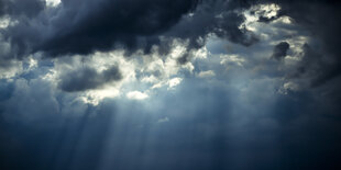 Sonnenstrahlen durchdringen eine dunkle Wolkendecke