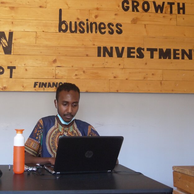 Mann mit laptob und Trinkflasche vor einer Holzwand "Growth, business, investment Mann mit laptob und Trinkflasche vor einer Holzwand "Growth, business, investment