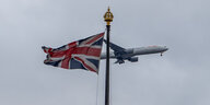 Ein Flugzeug fliegt an einer britischen Flagge vorbei